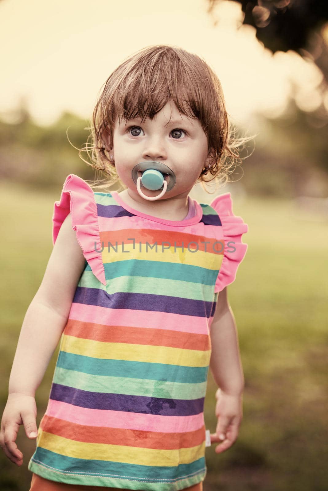 playful cute little girl cheerfully spending time while running in the spacious backyard on the grass