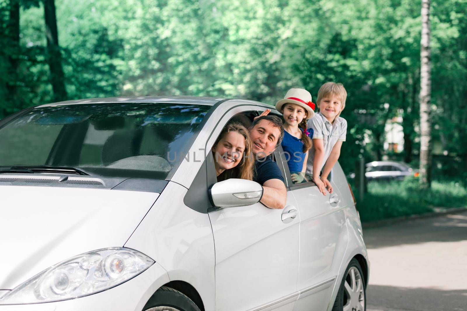 happy family with children sitting in a family car by SmartPhotoLab