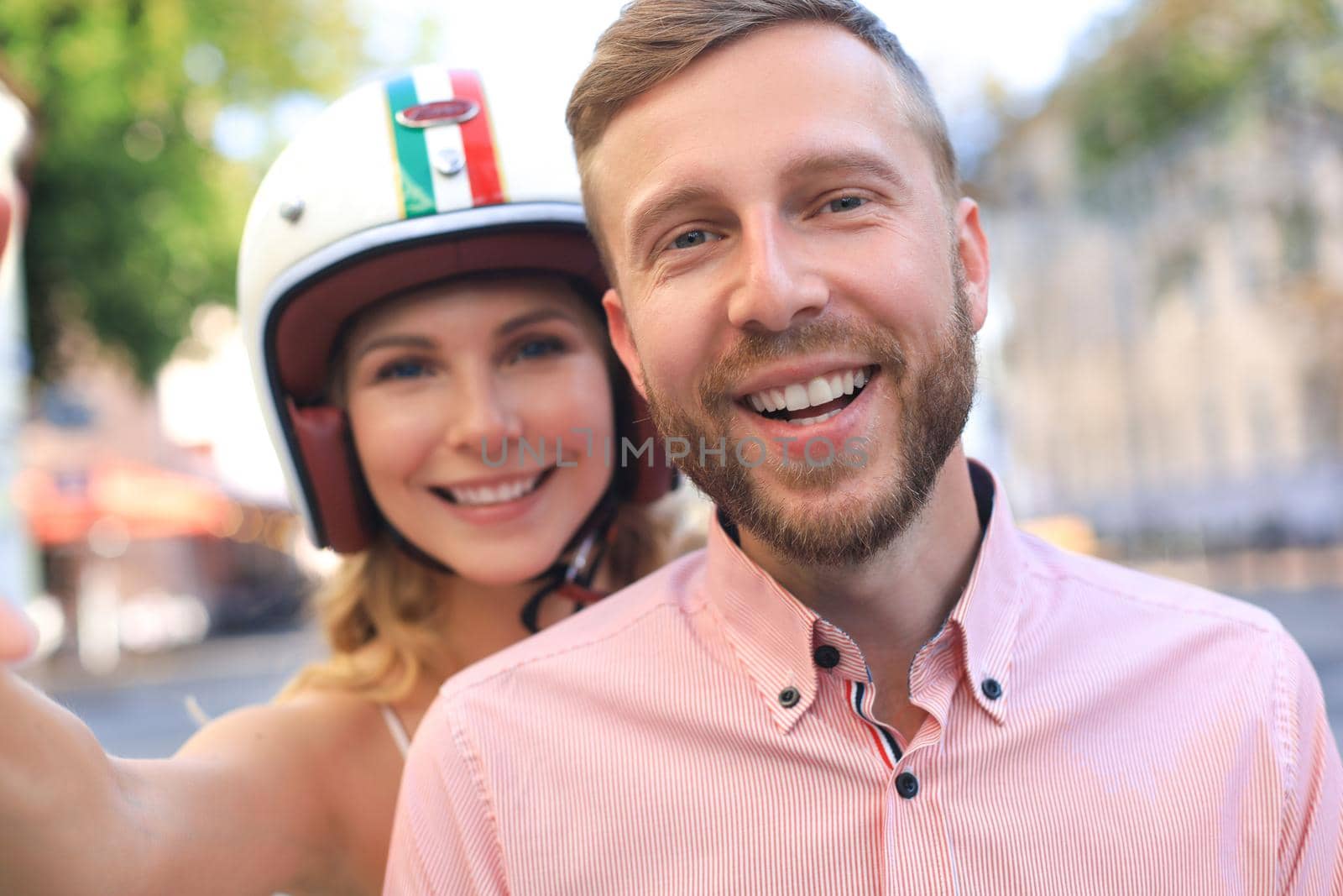 Happy young couple taking selfie while sitting on scooter outdoors. by tsyhun