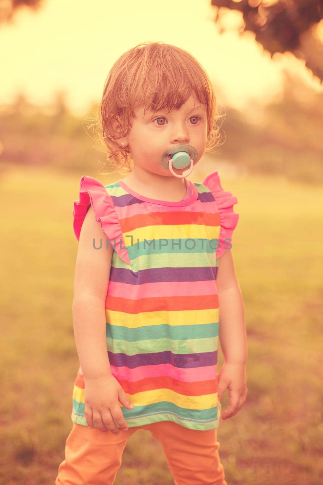 playful cute little girl cheerfully spending time while running in the spacious backyard on the grass