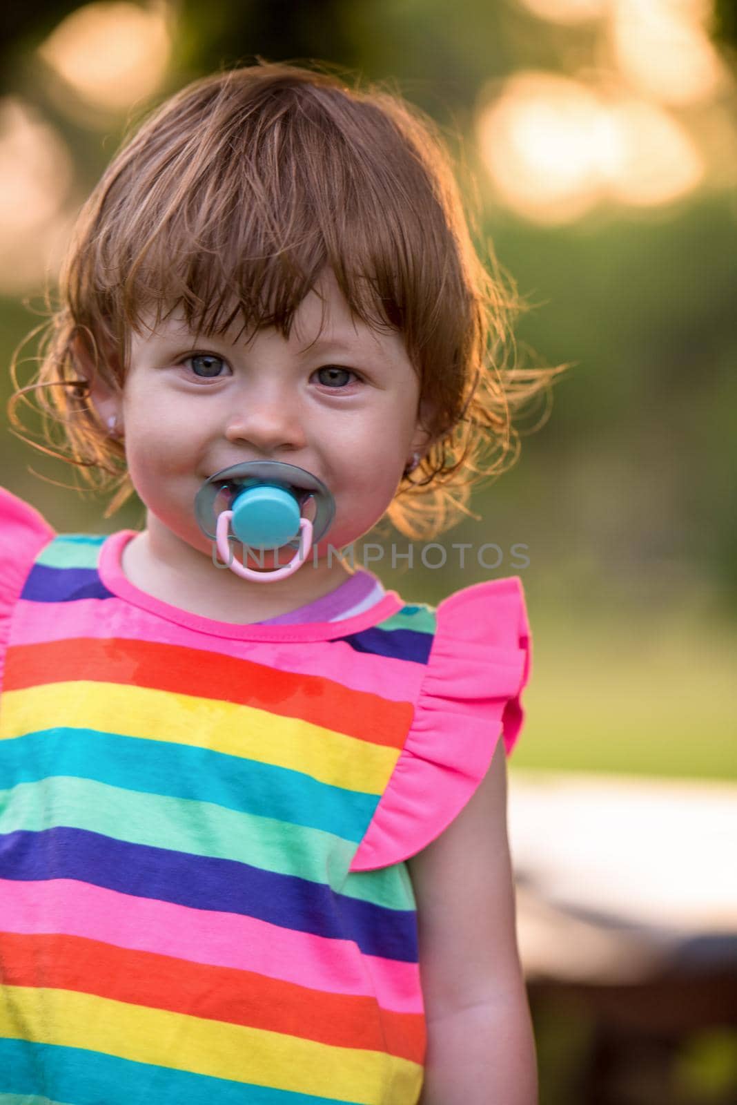 playful cute little girl cheerfully spending time while running in the spacious backyard on the grass