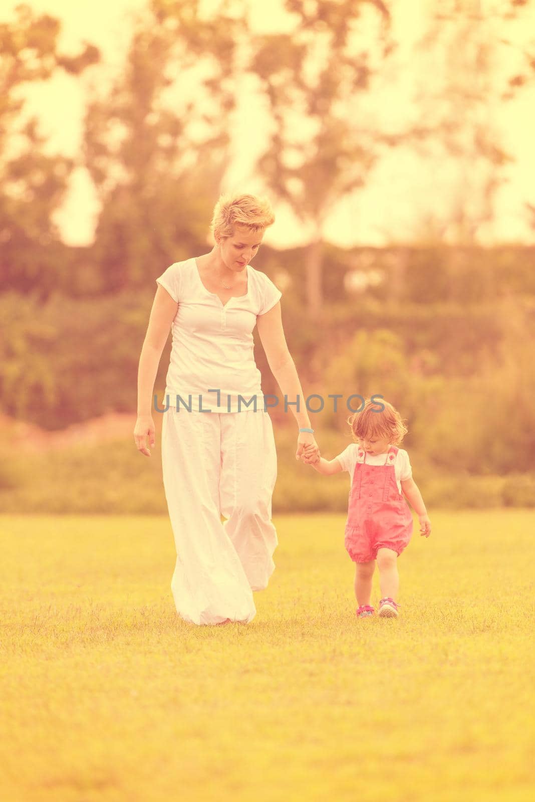 Young Mother and cute little daughter enjoying free time playing outside at backyard on the grass, happy family in nature concept