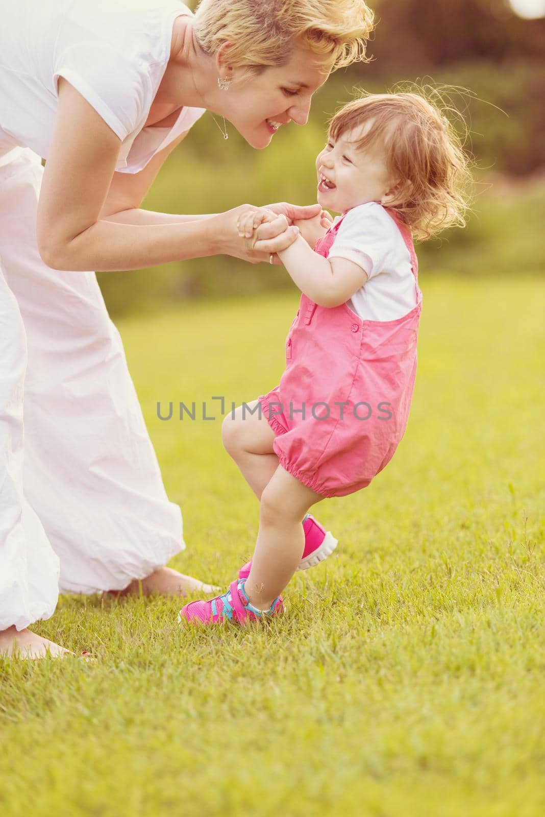 Young Mother and cute little daughter enjoying free time playing outside at backyard on the grass, happy family in nature concept