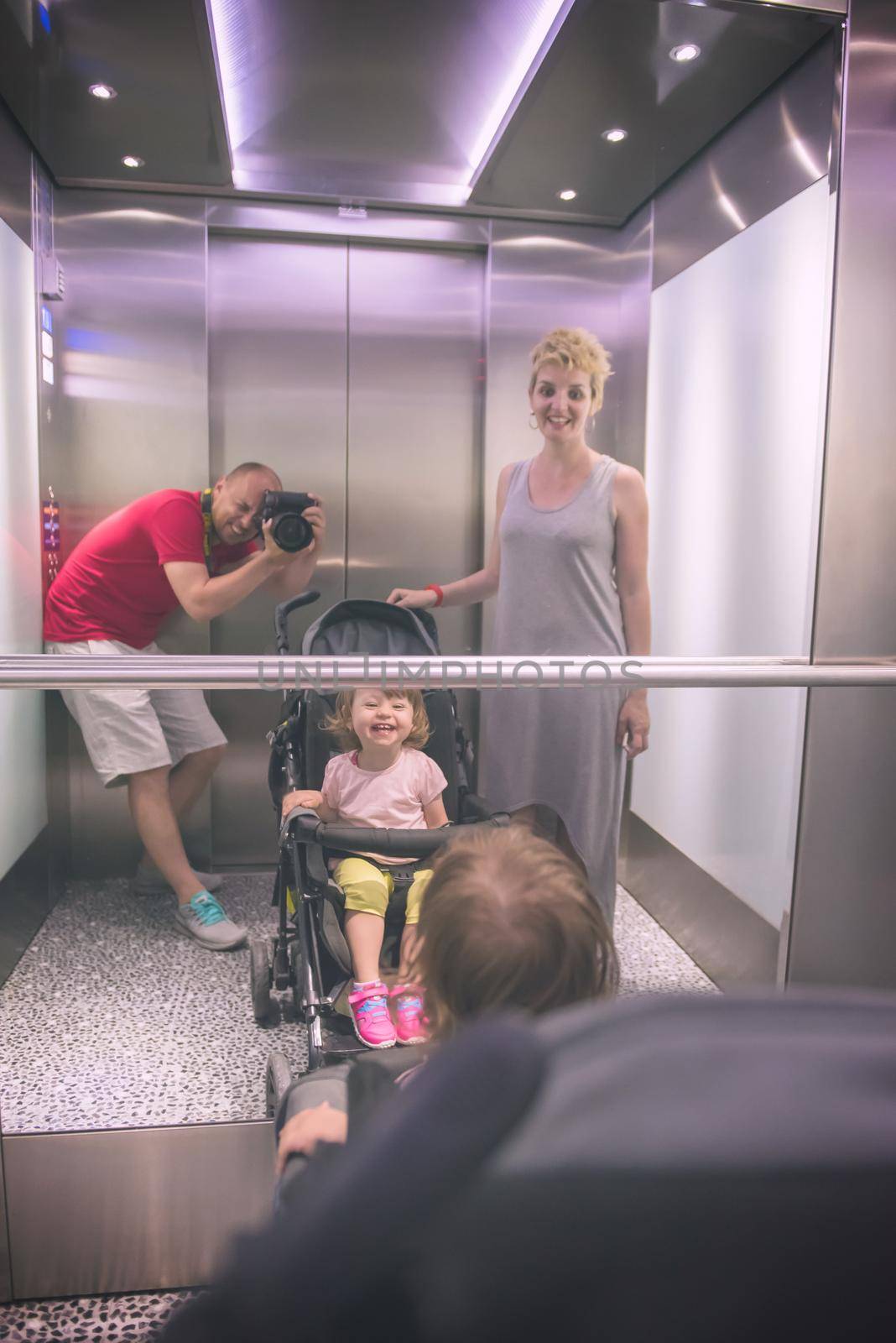 young father taking pictures of his happy family in the mirror of the elevator