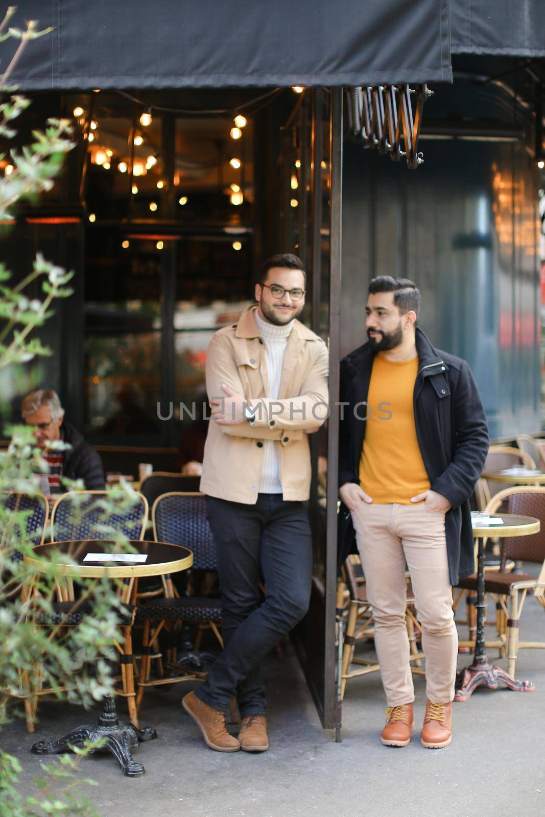 Male handsome friends standing and talking at street cafe. by sisterspro