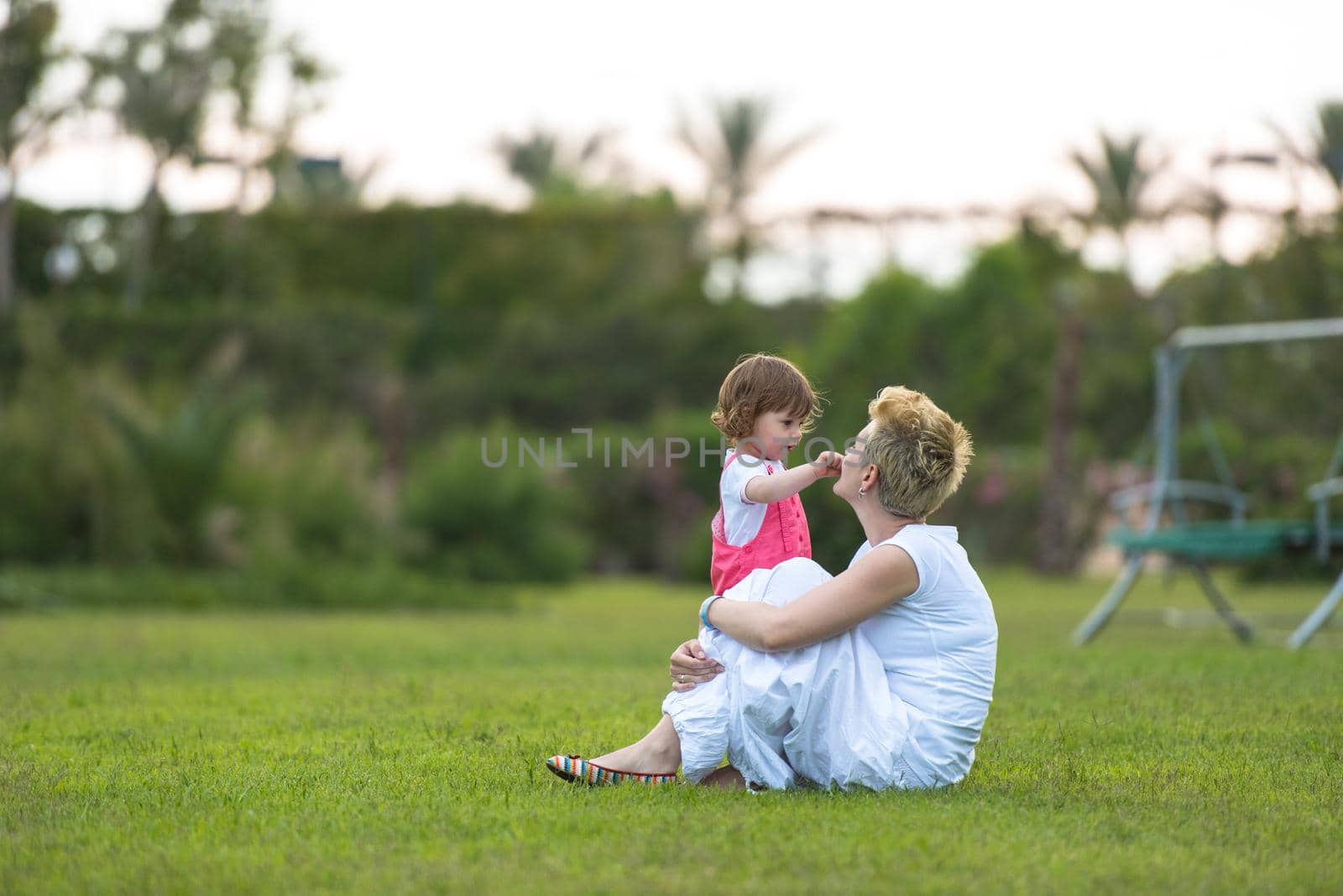 Young Mother and cute little daughter enjoying free time playing outside at backyard on the grass, happy family in nature concept