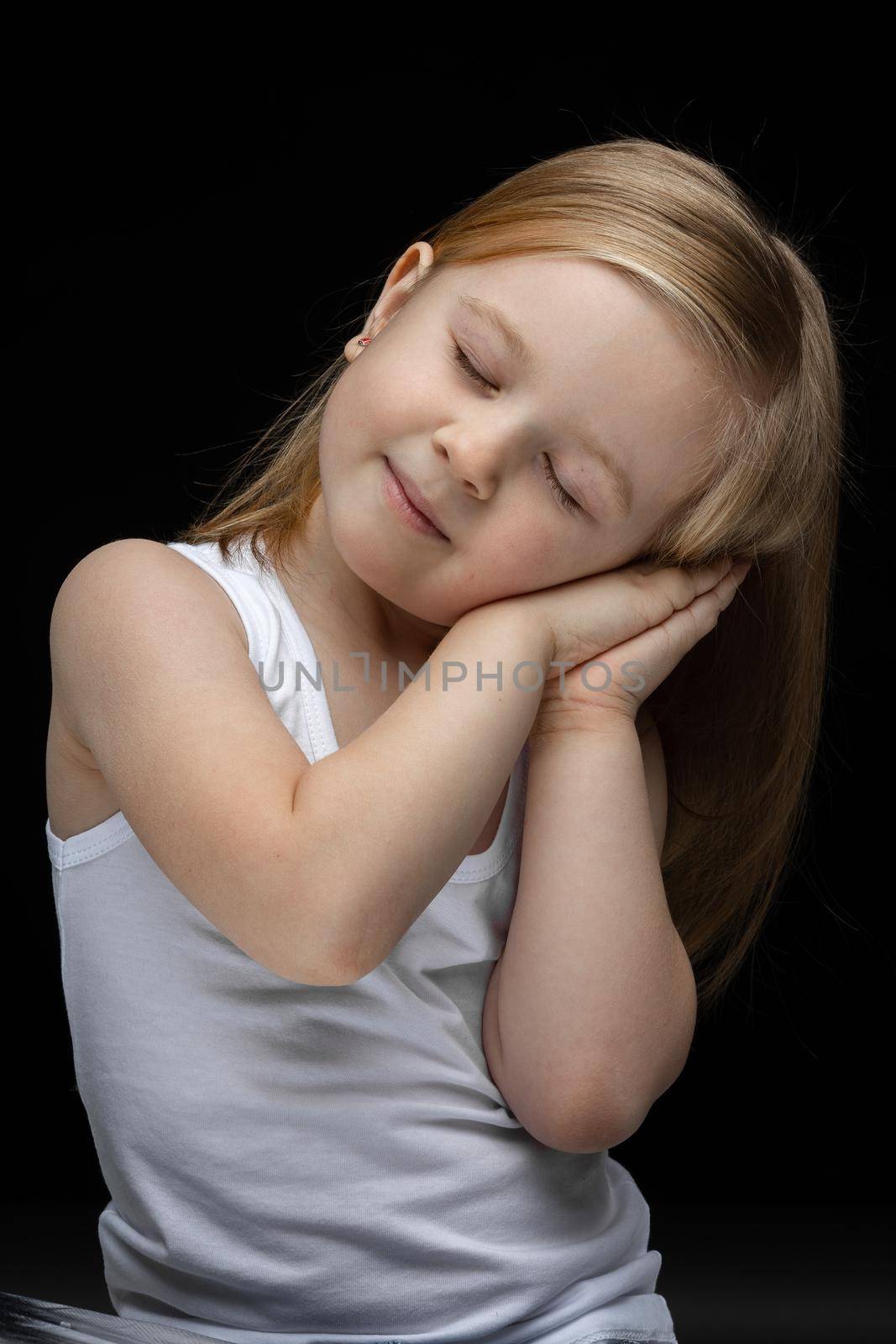 Pretty child feeling sleepy and smiling in photo studio by StudioLucky