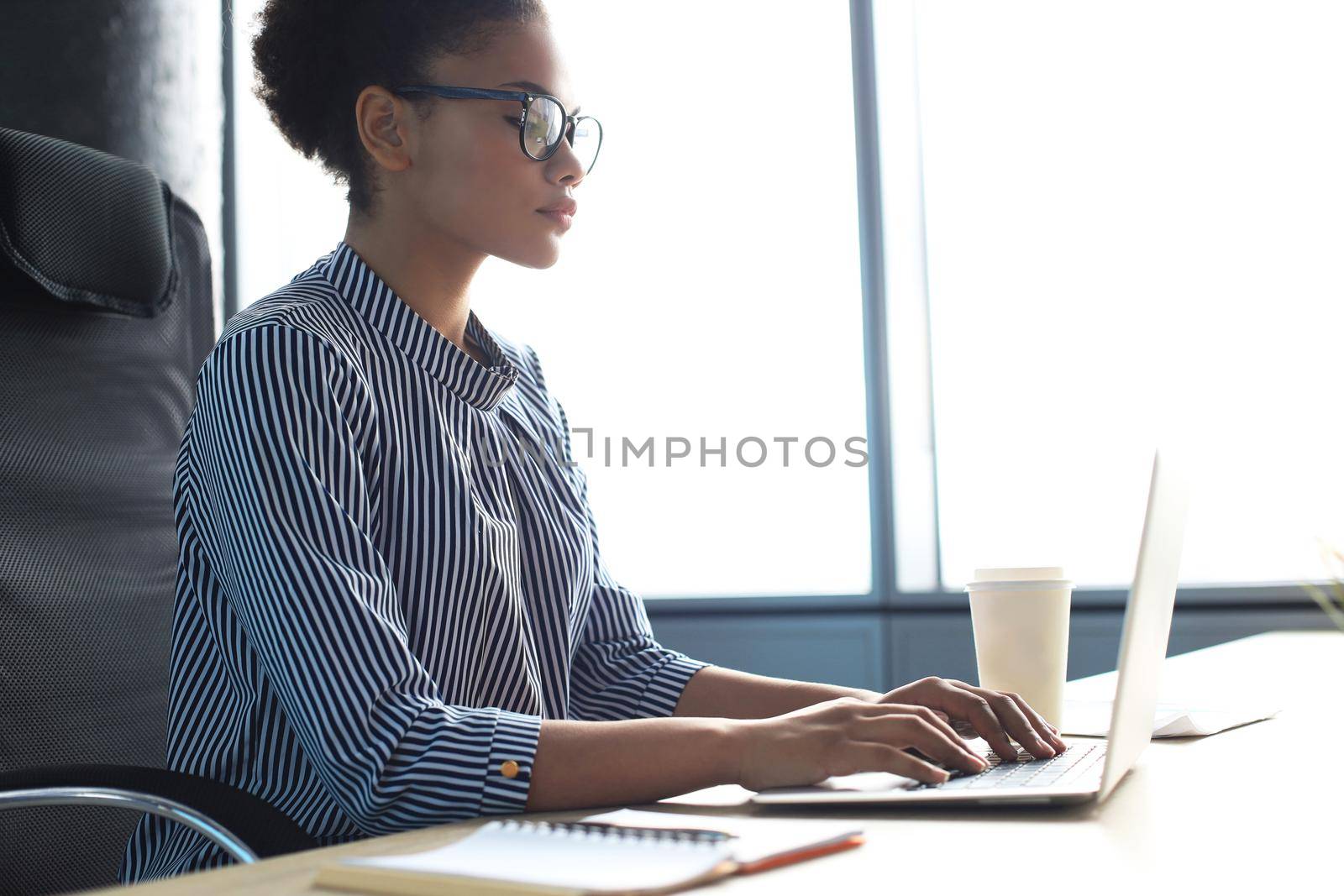 Portrait of beautiful young african american woman working with laptop while sitting at the table