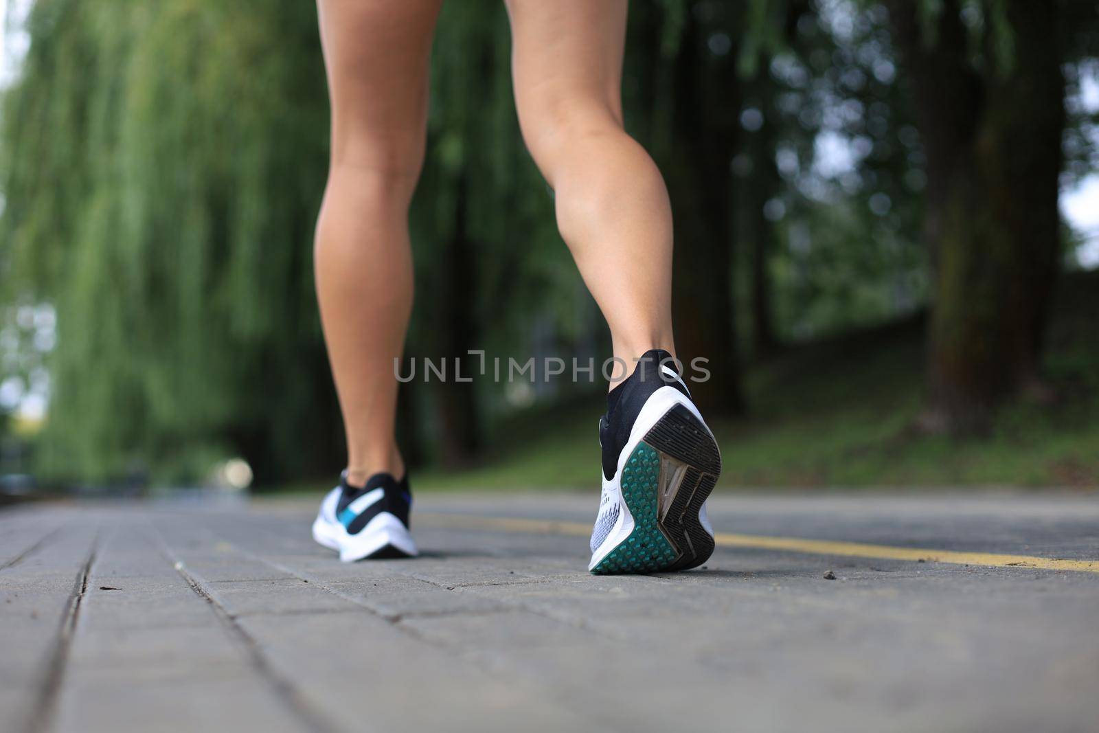 Runner feet running on road closeup on shoe, outdoor at sunset or sunrise