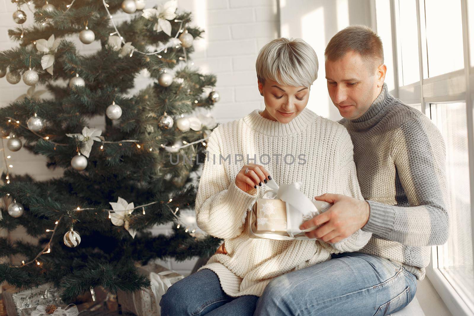 Family at home. Couple near christmas decorations. Woman in a gray sweater.