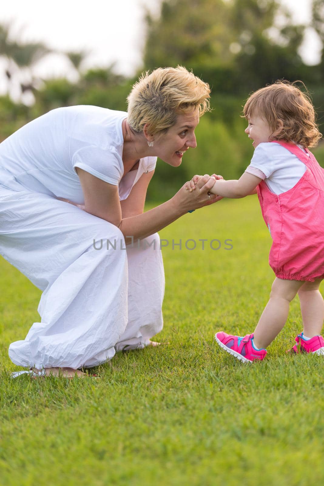 Young Mother and cute little daughter enjoying free time playing outside at backyard on the grass, happy family in nature concept