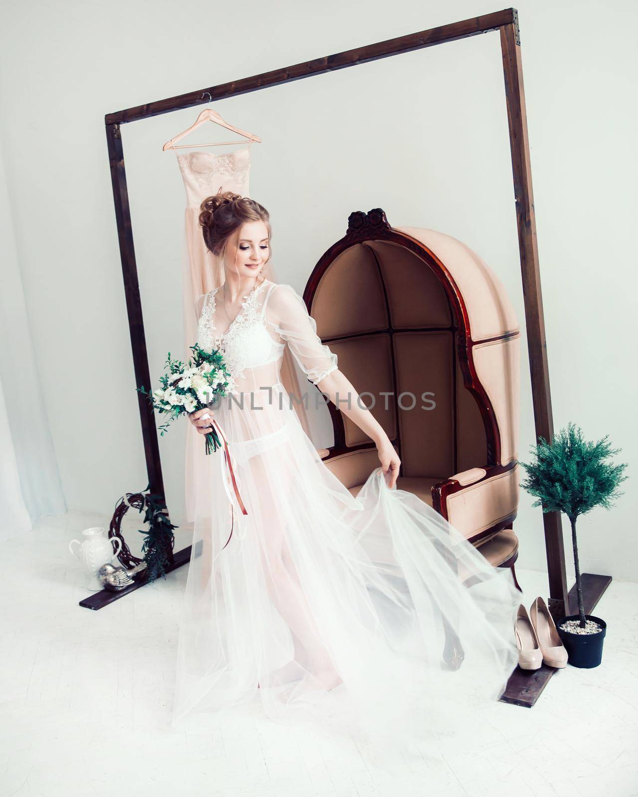 happy bride with a bouquet of flowers standing in the hotel room. Morning of the bride.