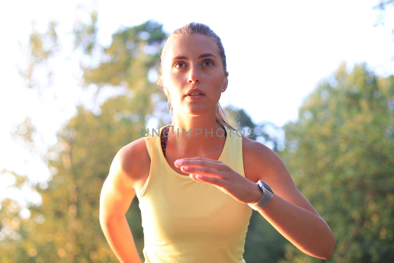 Young woman in sports clothing running while exercising outdoors. by tsyhun