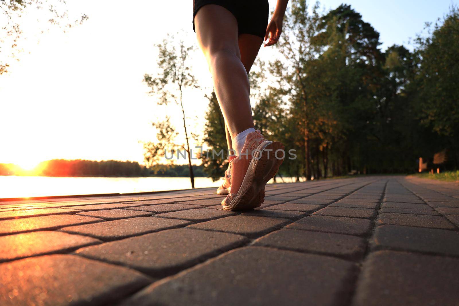 Runner feet running on road closeup on shoe, outdoor at sunset or sunrise