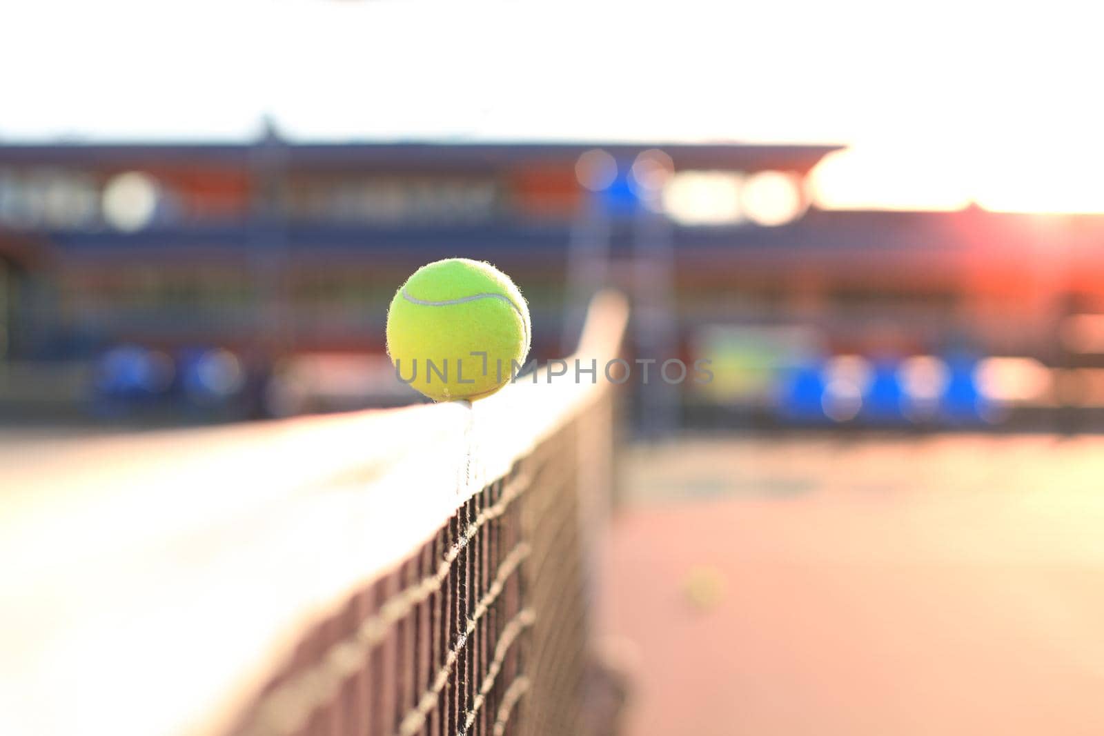 Bright greenish yellow tennis ball hitting the net