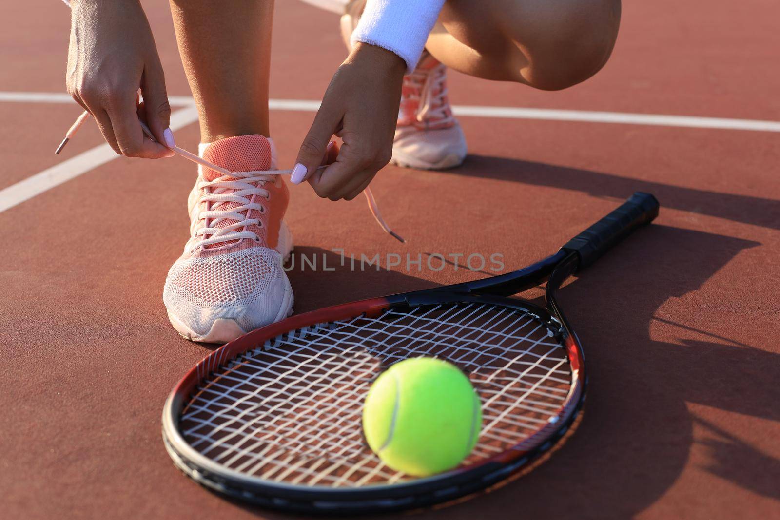 Sports woman getting ready for playing tennis tying shoelaces on outdoor. by tsyhun