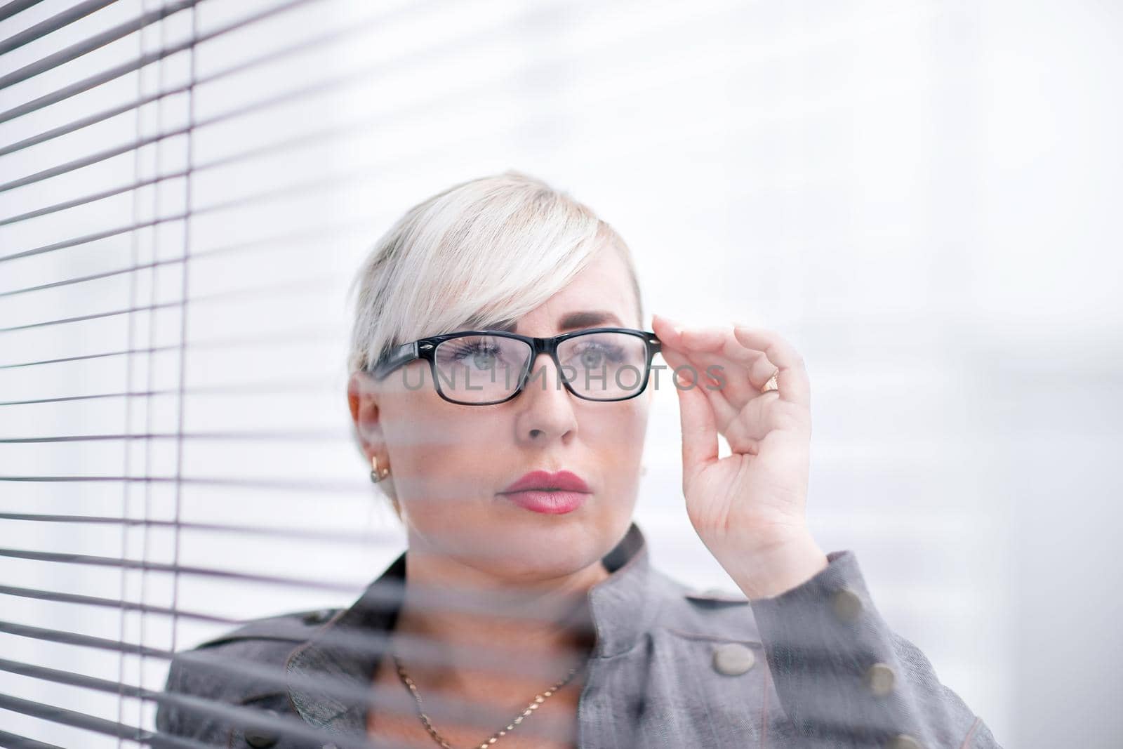close up. business woman looks somewhere through the office window. business people