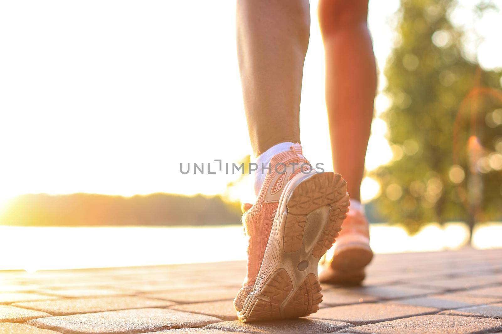 Runner feet running on road closeup on shoe, outdoor at sunset or sunrise. by tsyhun