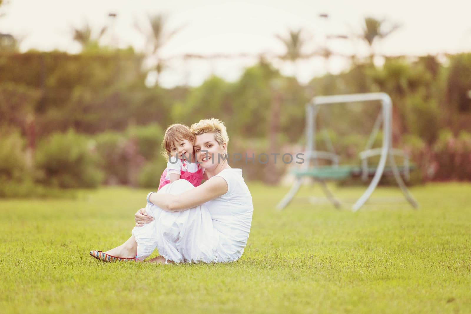 Young Mother and cute little daughter enjoying free time playing outside at backyard on the grass, happy family in nature concept