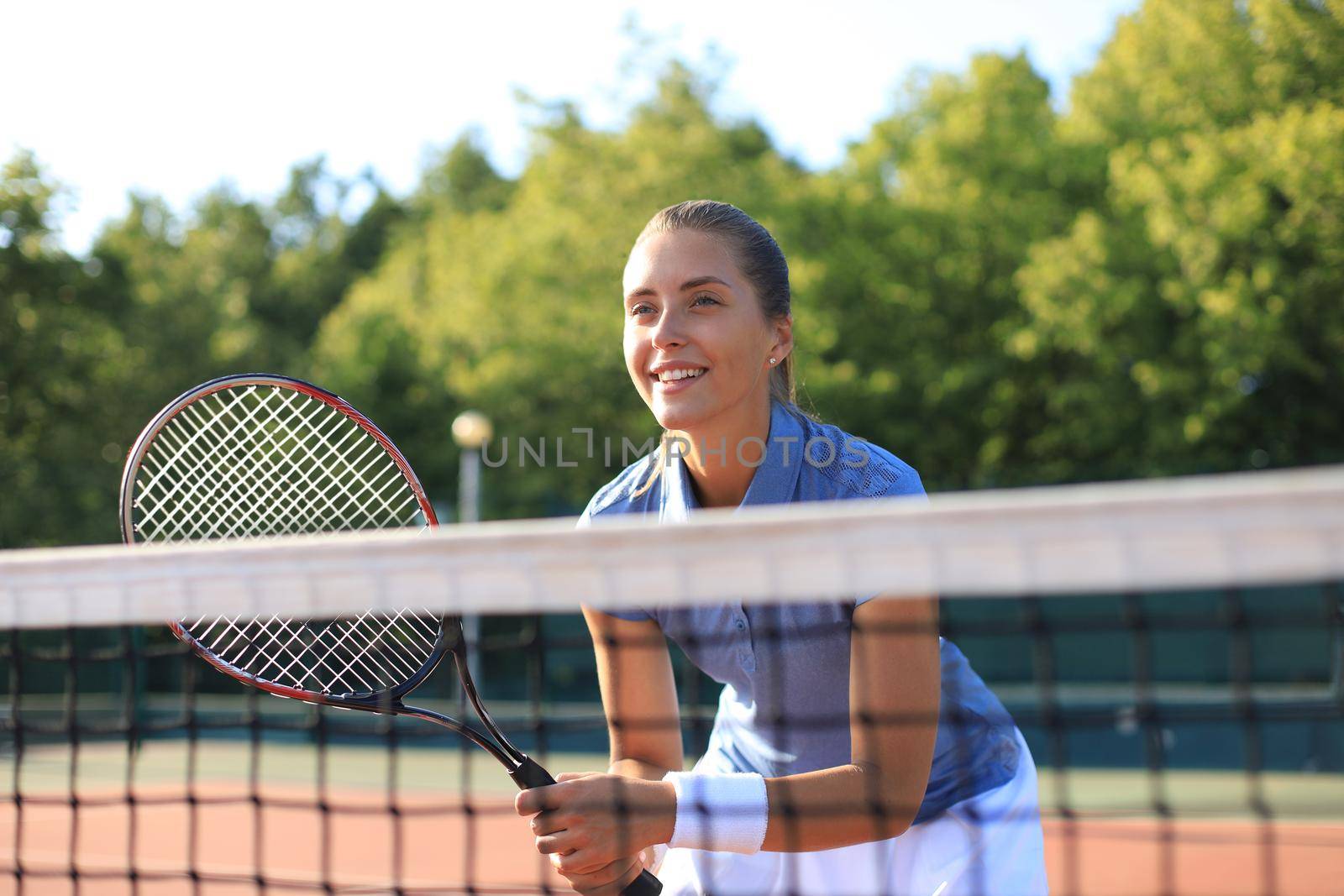 Pretty sportswoman with racquet at the tennis court. Healthy lifestyle