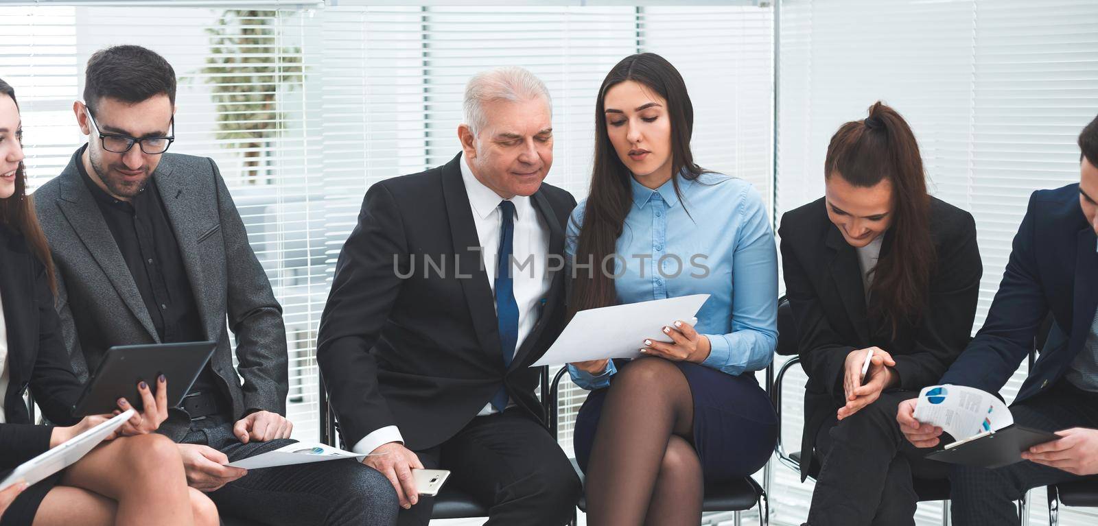 group of employees discussing financial documents before the meeting.