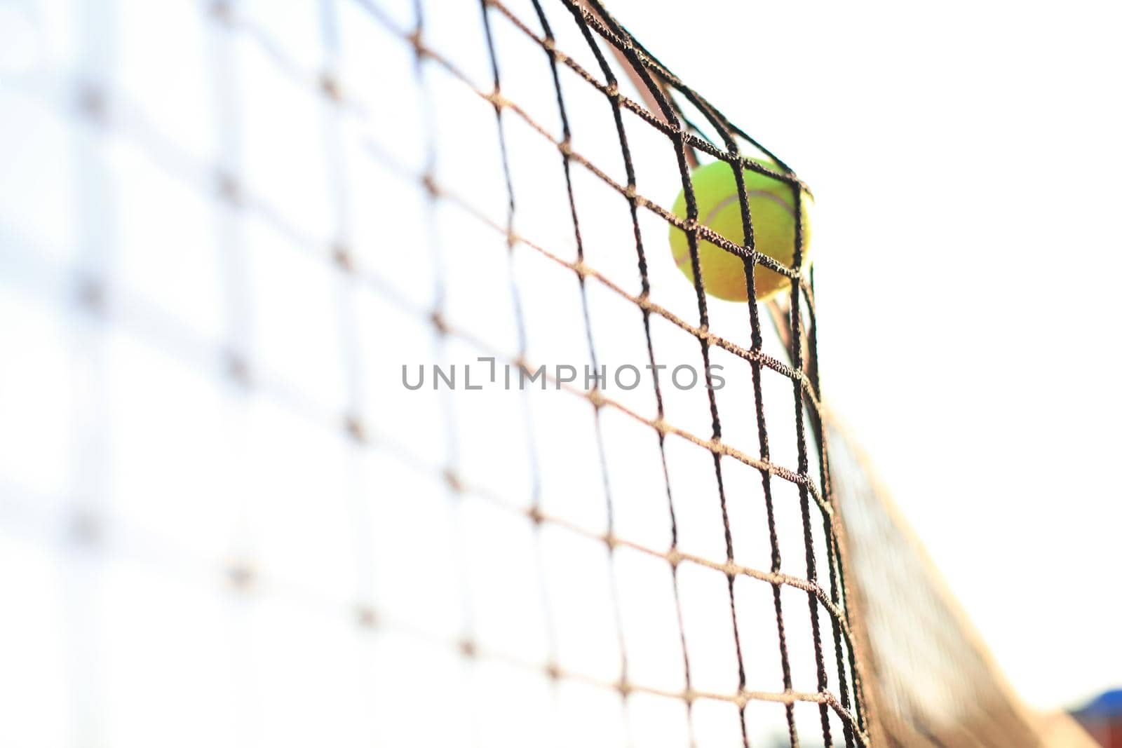 Bright greenish yellow tennis ball hitting the net