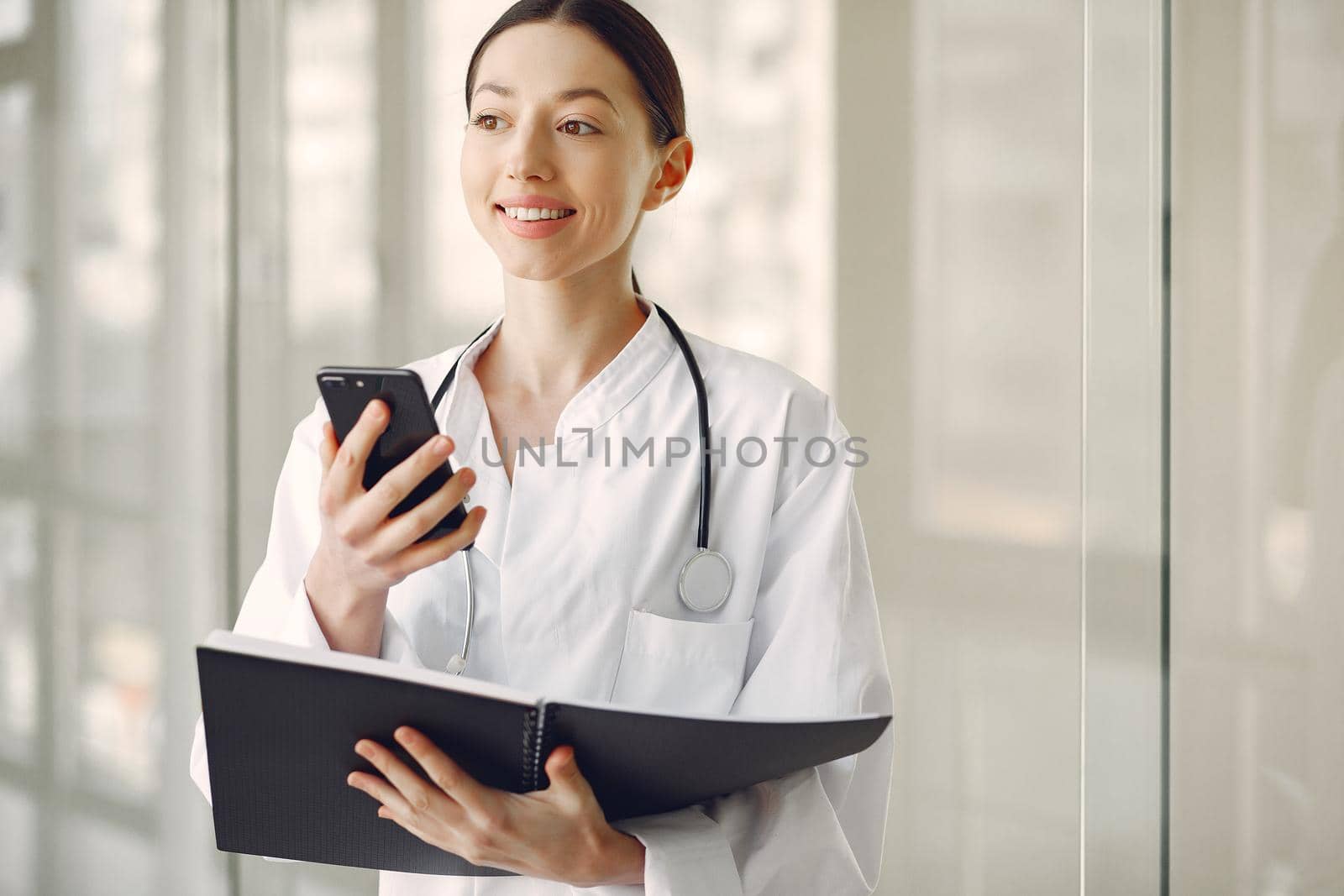 Woman in a uniform. Doctio with a stethoscope. Brunette in a hall.