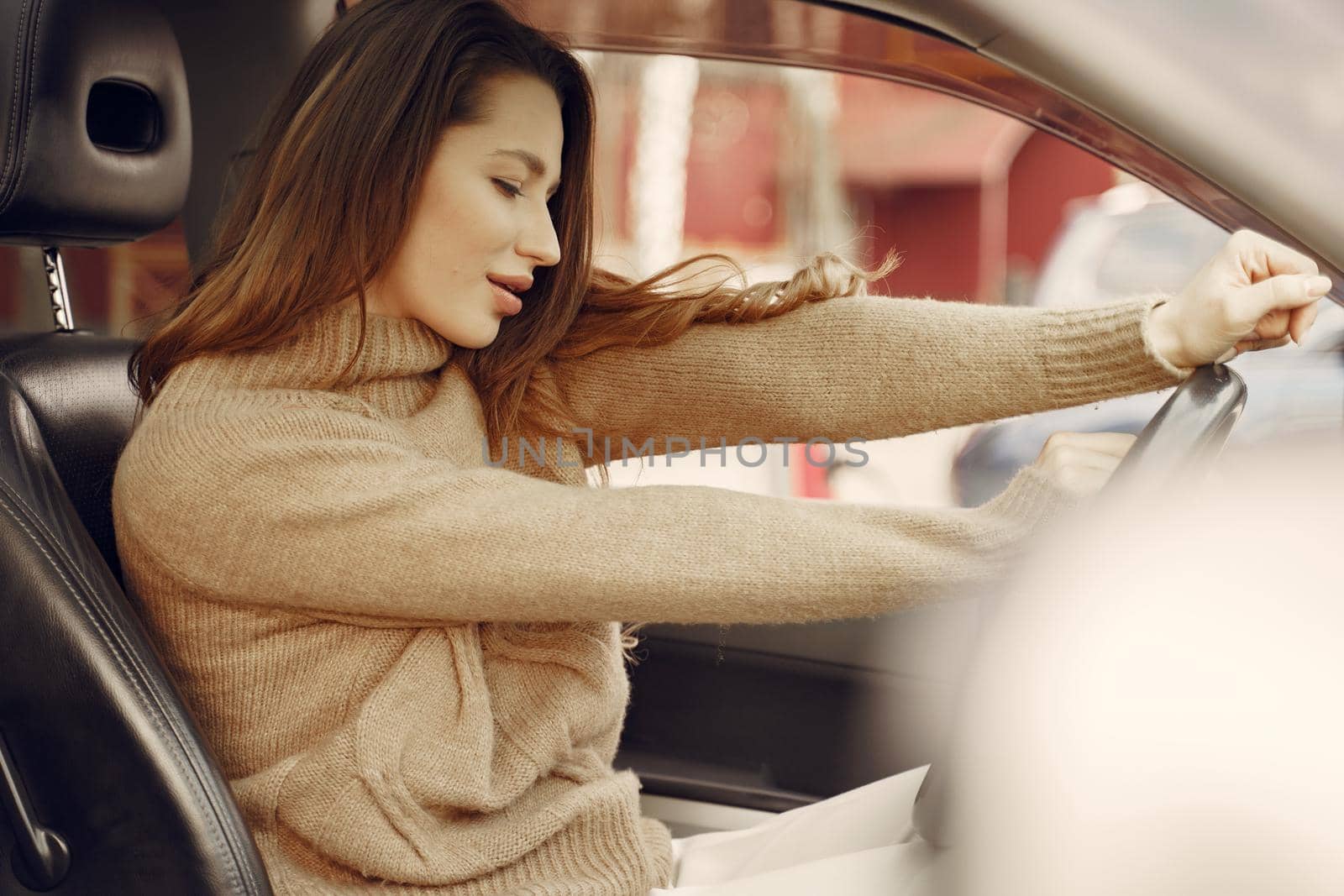 Woman sitting in a car. Lady in a brown sweater.