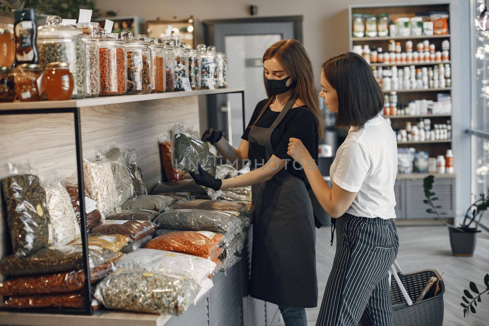 Brunette chooses food. Lady is holding a shopping cart.Girl in a white shirt in the supermarket.Beautiful woman in the store buys groceries.