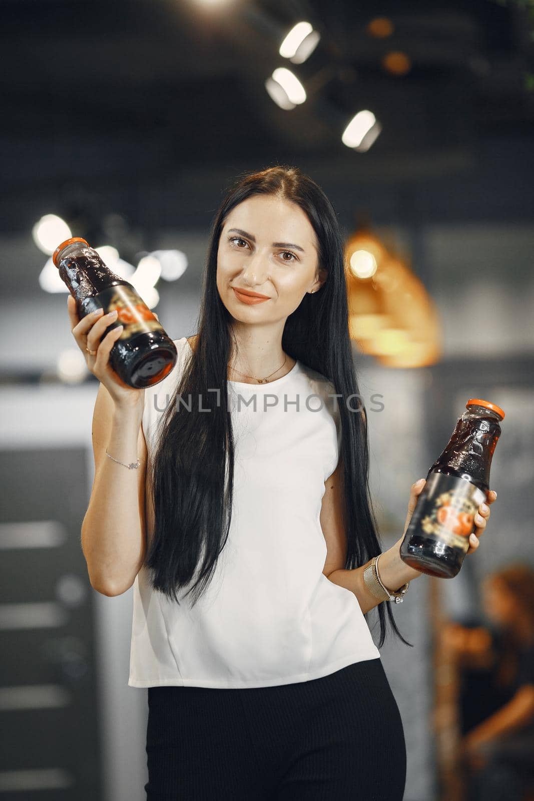 Woman in a white shirt in the supermarket. Brunette looks at the camera and smiles.