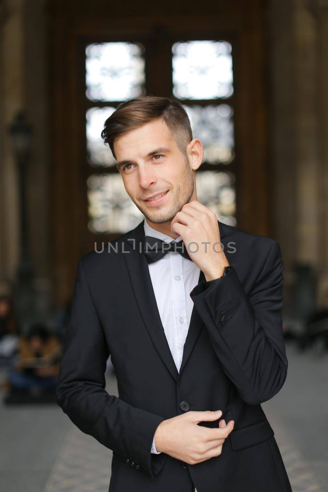 Young groom standing and waiting, wearing black suit and bow tie. by sisterspro