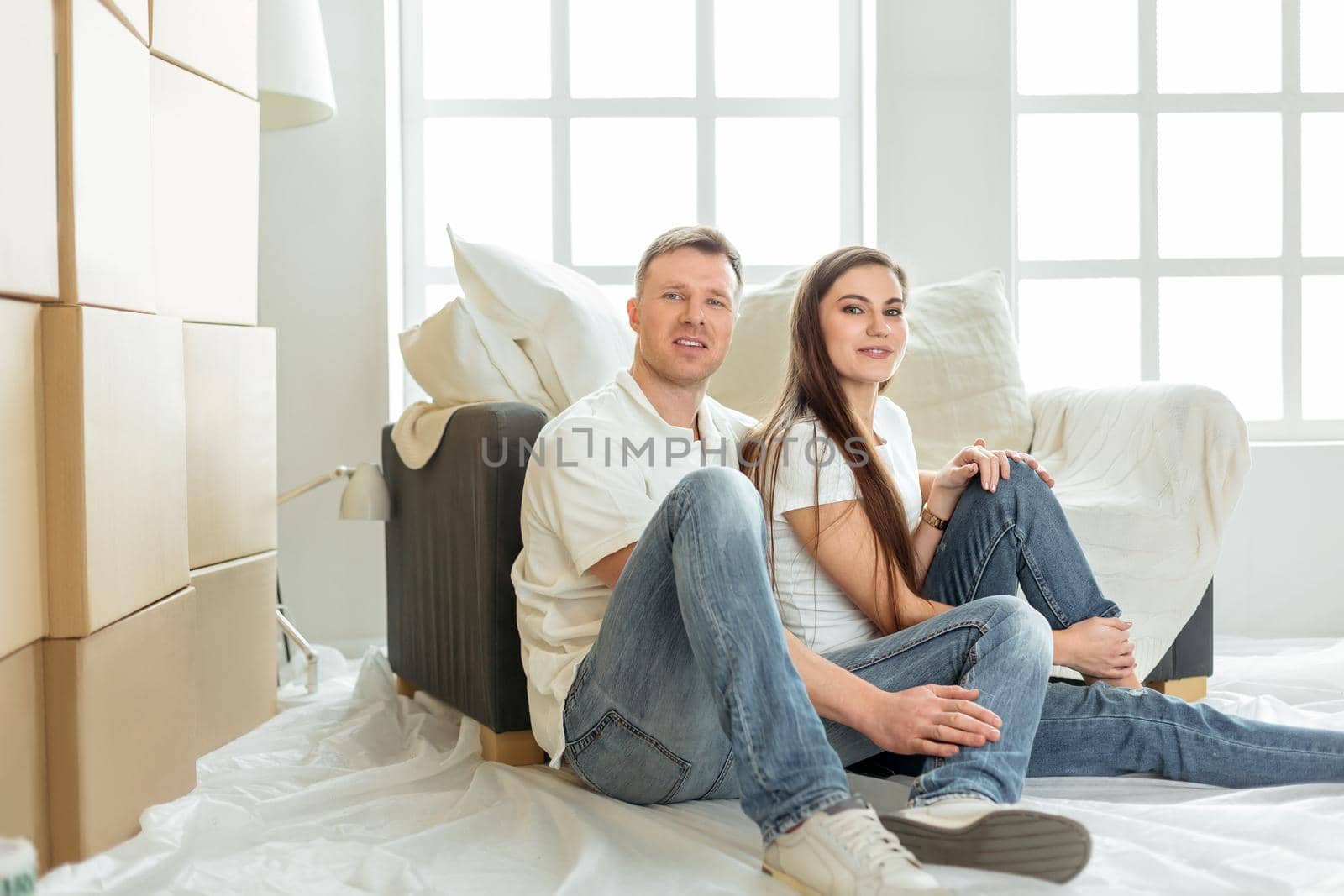 young family sitting on the floor in the new living room. photo with copy-space