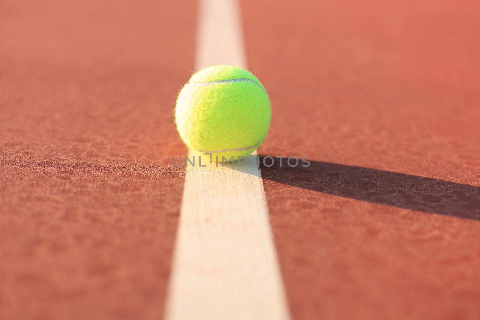 Bright greenish yellow tennis ball on the line. by tsyhun