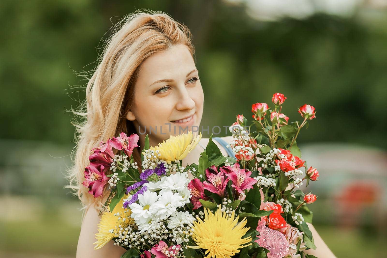 smiling woman with a bouquet of flowers on a blurred background of the Park