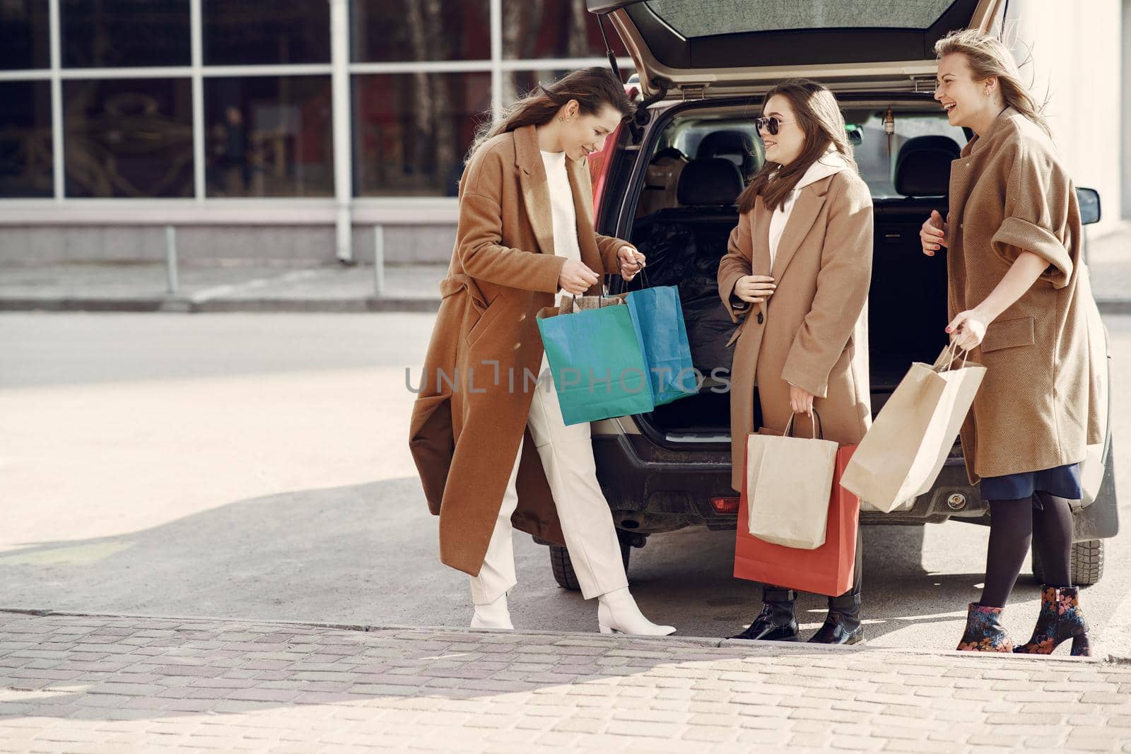 Girls on a shopping. Friends walks. Women with a shopping bags. Lady near trunk of the car.
