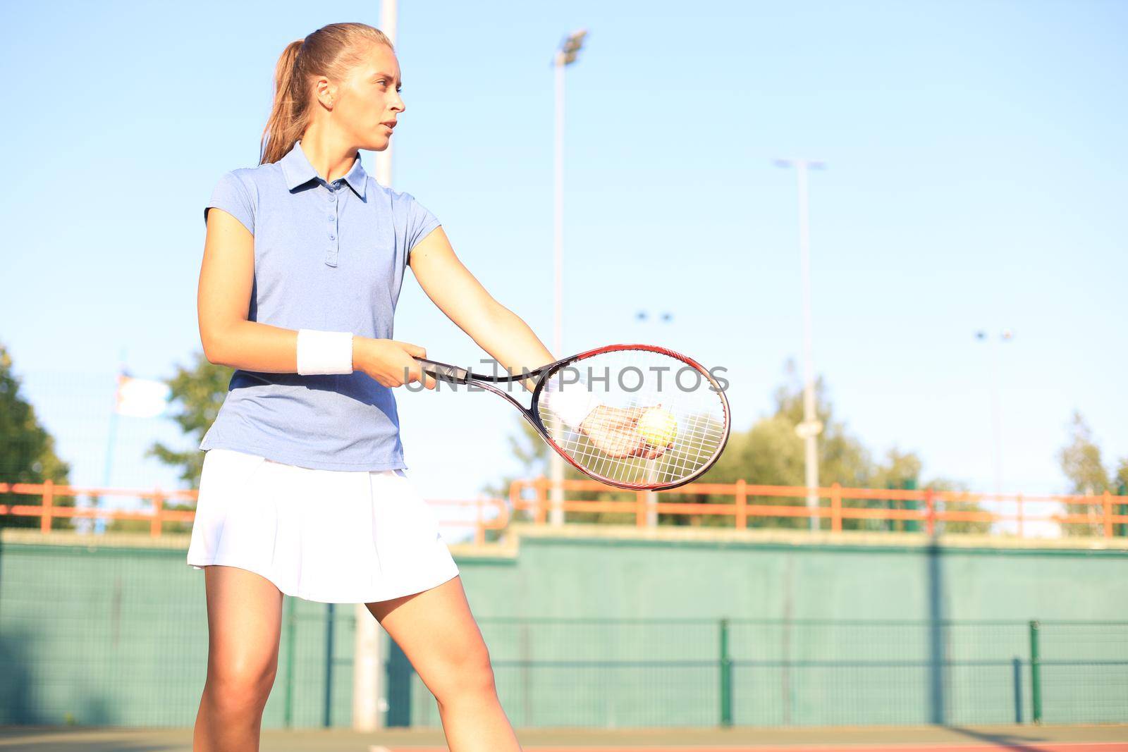 Pretty sportswoman with racquet at the tennis court. Healthy lifestyle