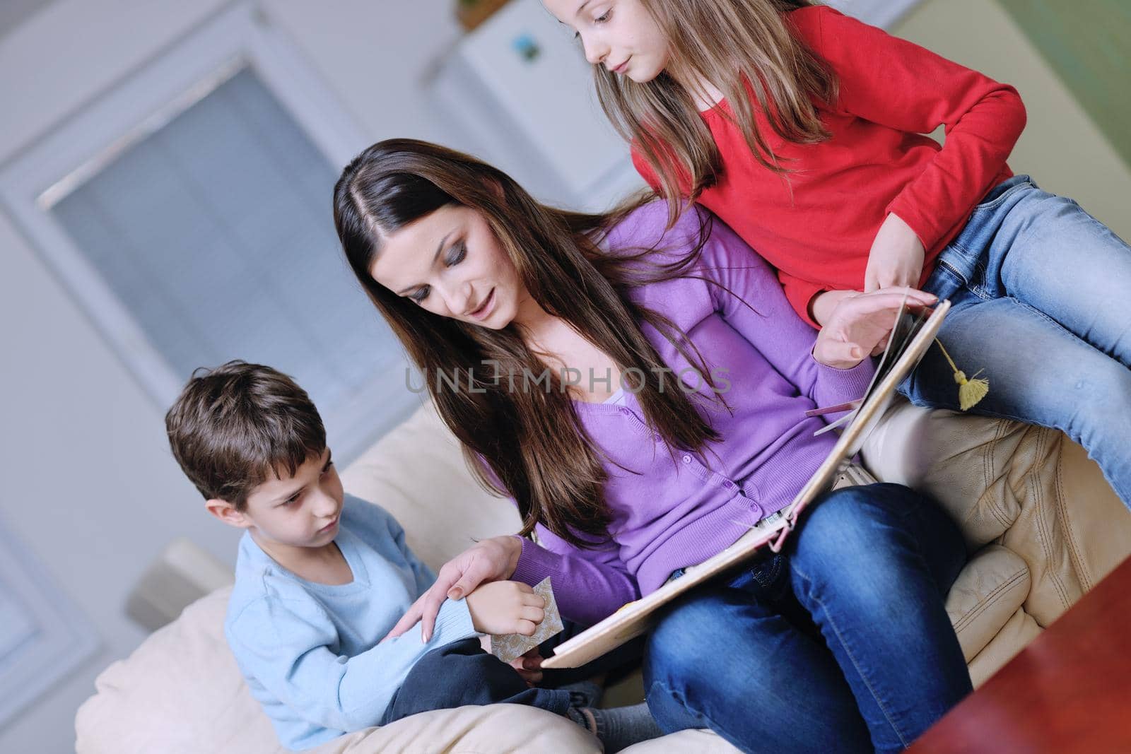 young mother read book to their kids at modern new home living room indoor