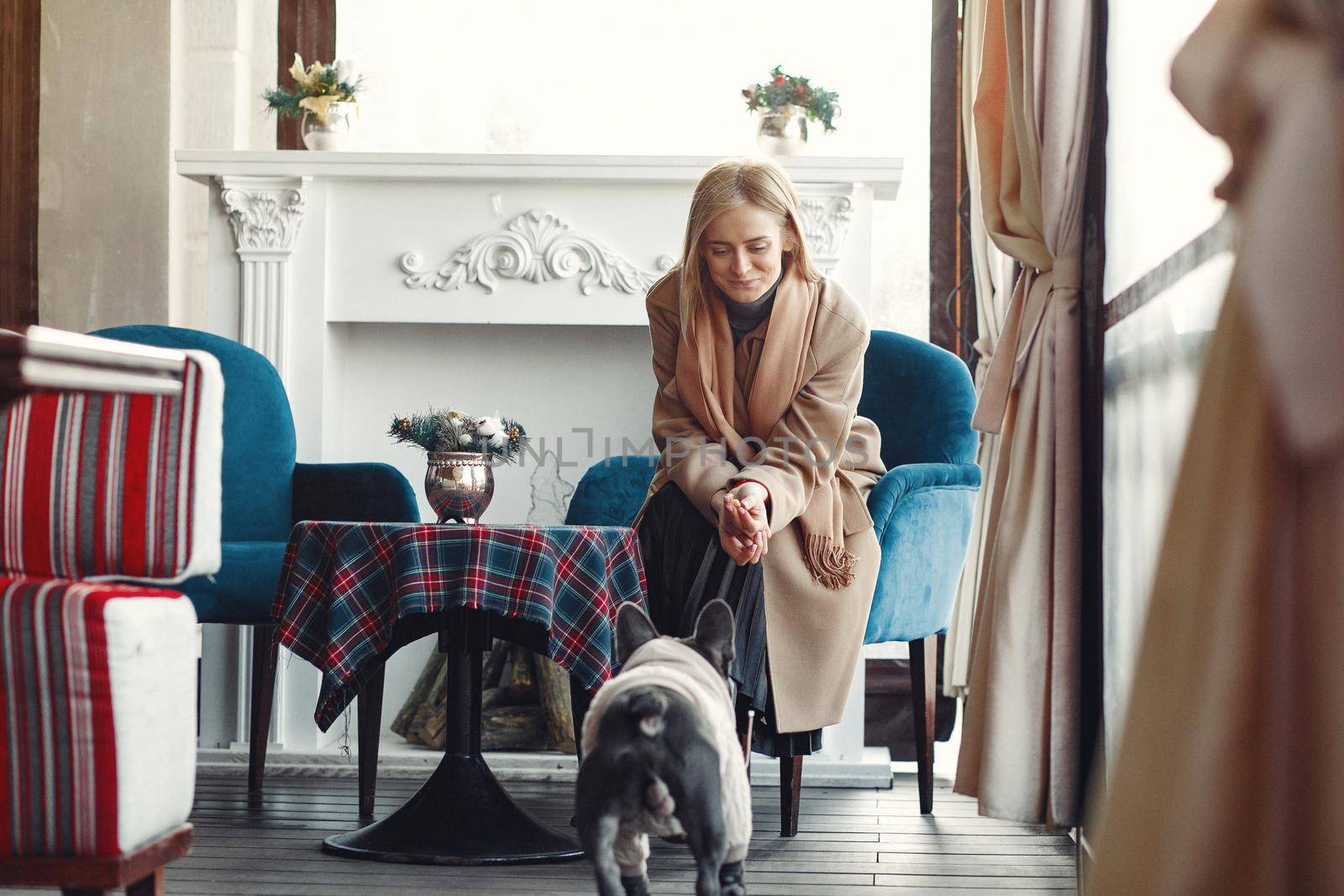 Woman with dog. Lady in a brown coat. Girl play with bulldog. Woman in a cafe.