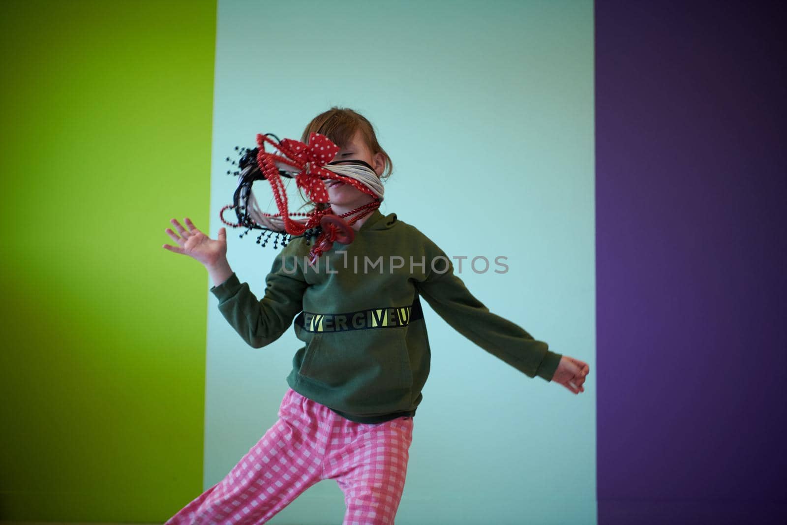 funny child girl playing at home. girl having fun and dancing wearing mothers jewelry. recreation and entertainment at home