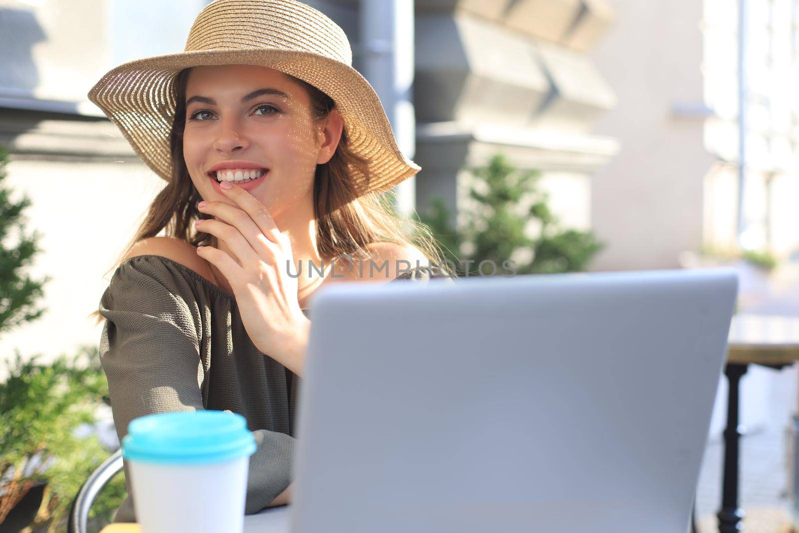 Happy nice woman working on laptop in street cafe