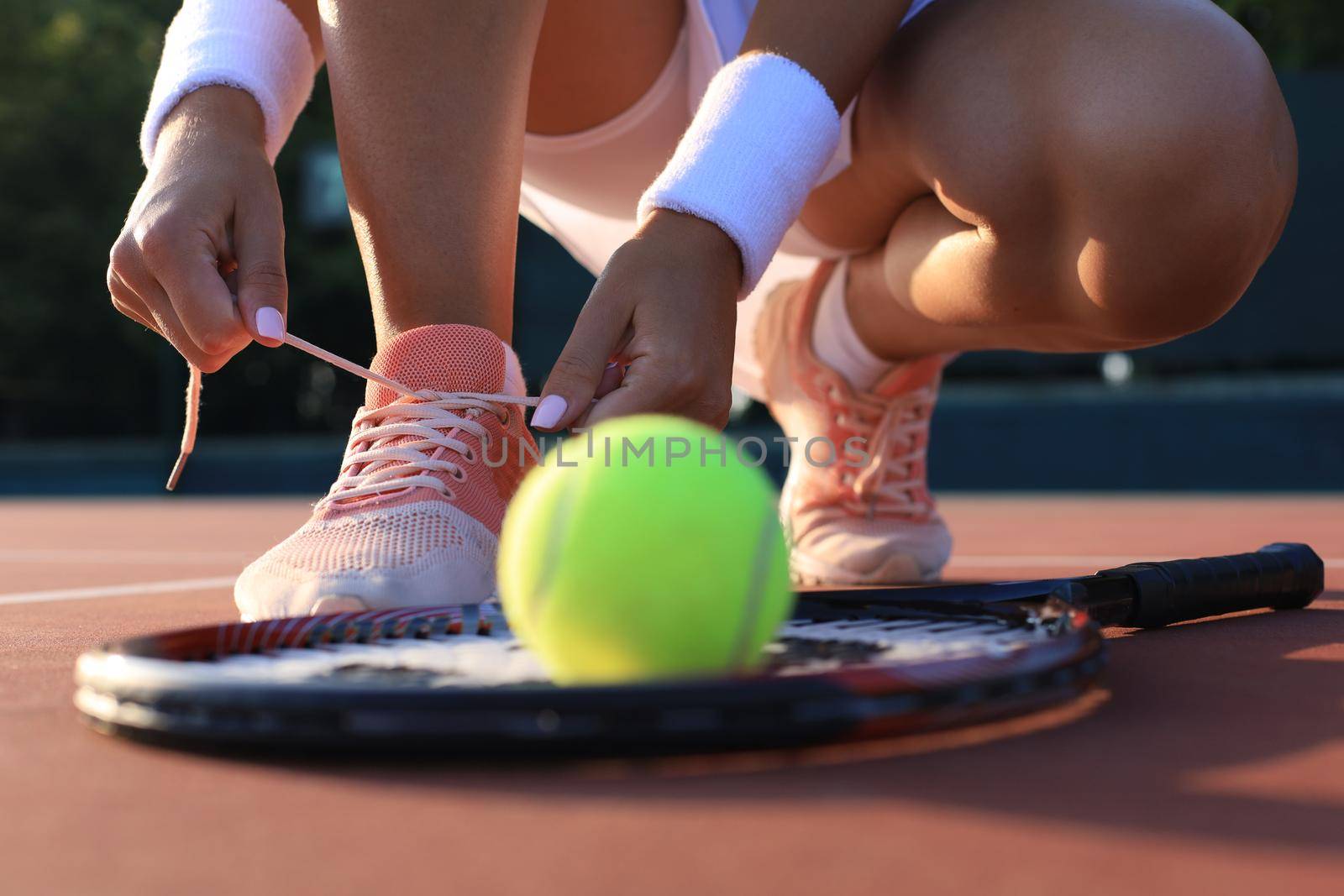 Sports woman getting ready for playing tennis tying shoelaces on outdoor