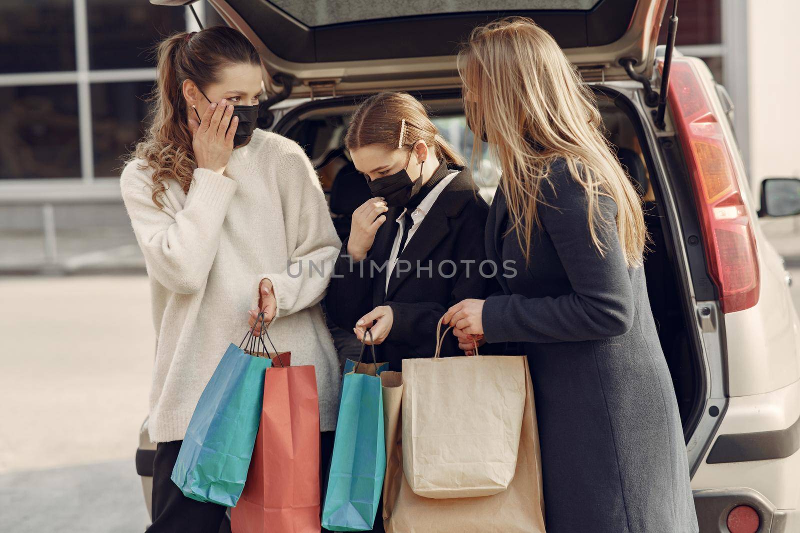 Girls on a shopping. People in a masks. Women with a shopping bags. Lady near trunk of the car. Coronavirus theme.