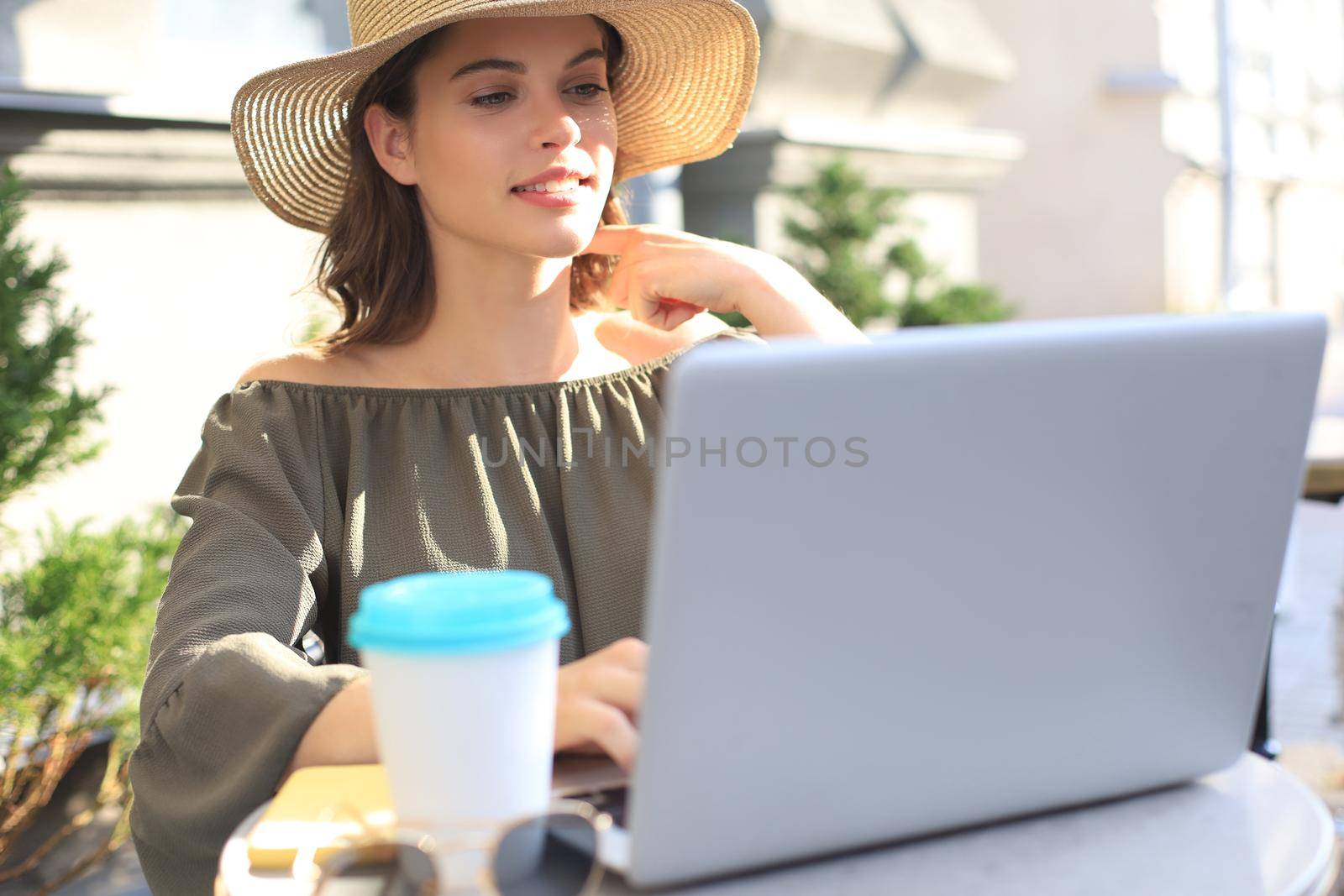 Happy nice woman working on laptop in street cafe