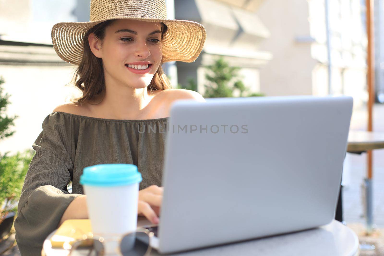 Happy nice woman working on laptop in street cafe