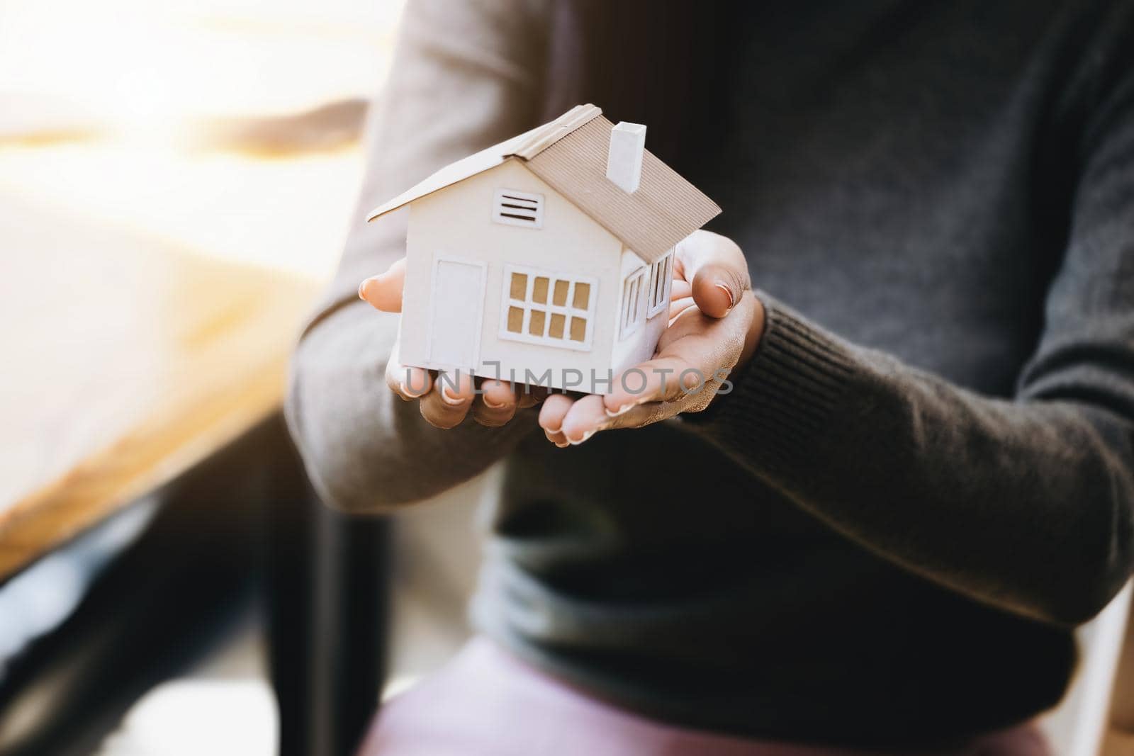 Female hand holding a house model, insurance concept and home loan