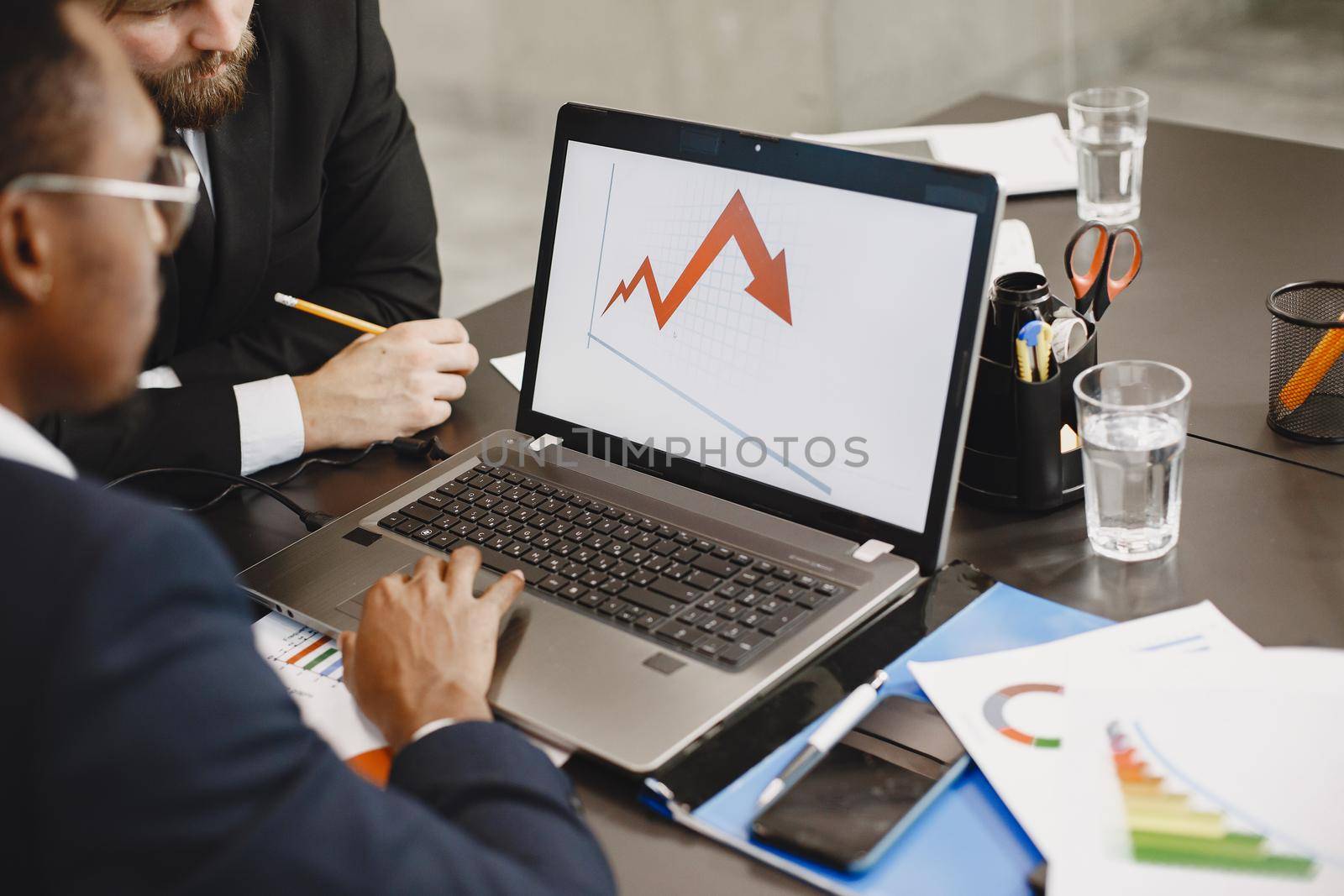 African man in a black suit. International partners. People sitting at the table with laptop.