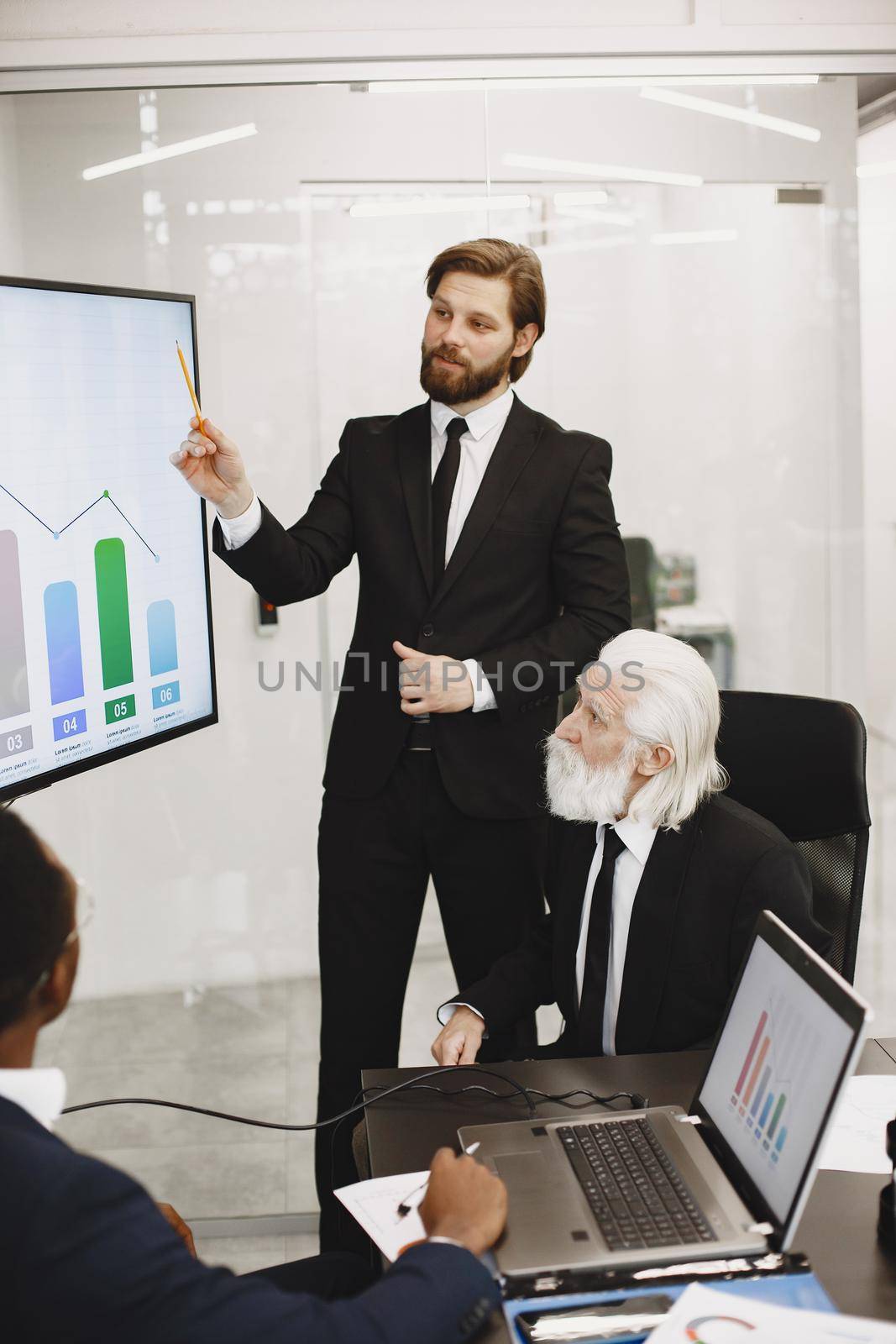 African man in a black suit. International partners. Young guys with senior man.