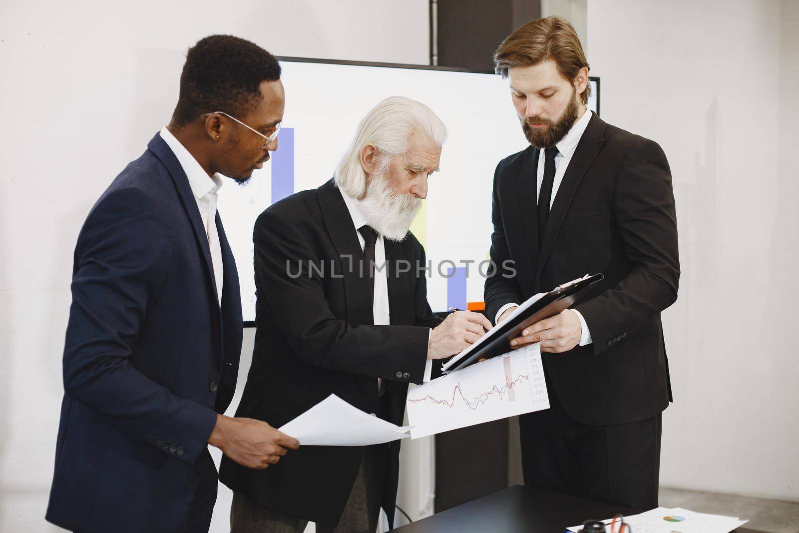 African man in a black suit. International partners. Young guys with senior man.