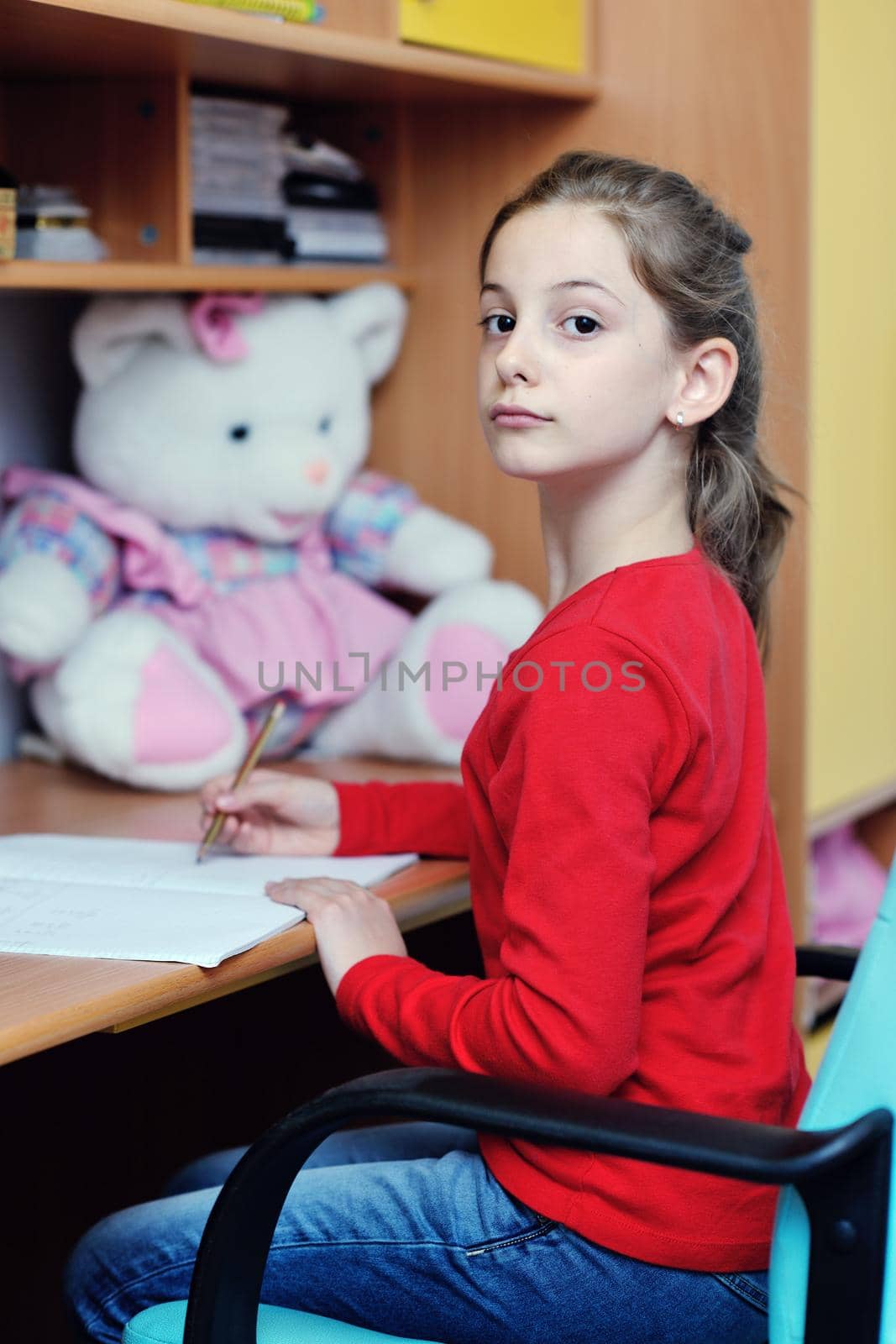 happy young school girl doing homework at home