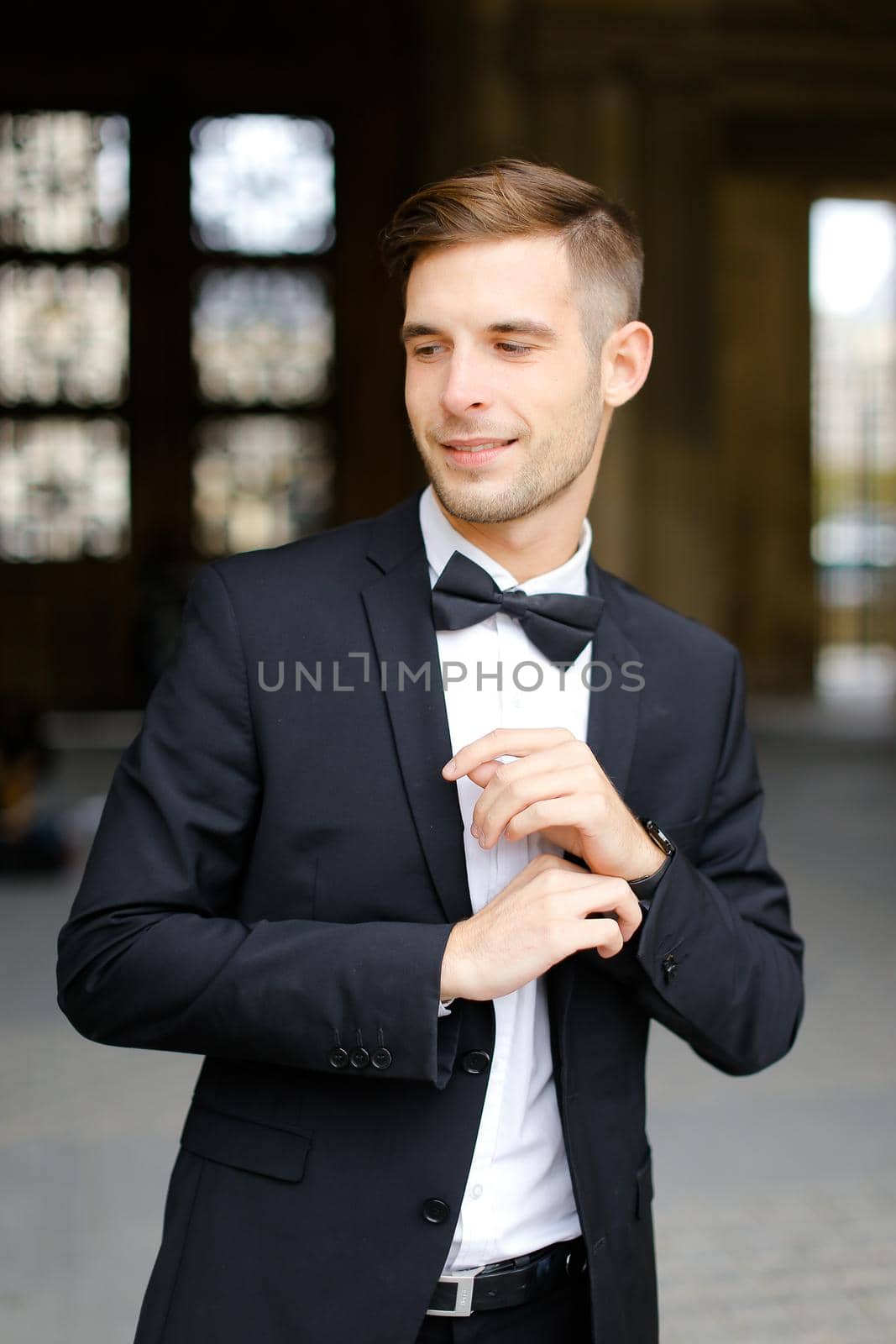 Young handsome man standing and posing, wearing black suit and bow tie. by sisterspro